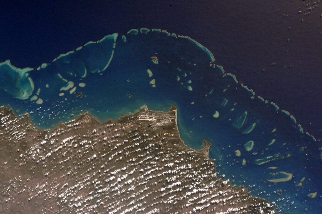 Aerial view of the Great Barrier Reef showing bleached white coral patches amid turquoise water