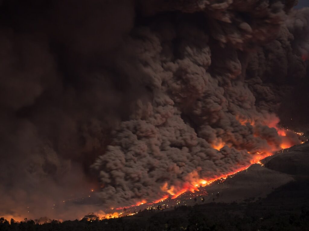 Aerial view of a large wildfire burning across dry grassland in the Texas panhandle, with smoke plumes rising into the sky.
