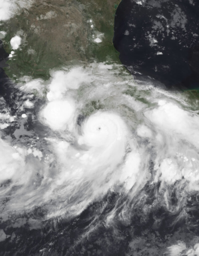 Satellite image of Hurricane John approaching the coast of southern Mexico with a well-defined eye and spiral bands of clouds.