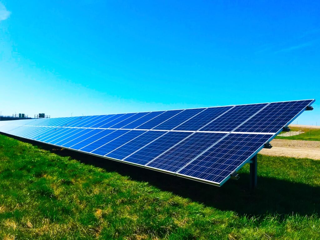 Solar panels on a rooftop and in a ground-mounted solar farm under a bright sky, representing photovoltaic systems driving global capacity.