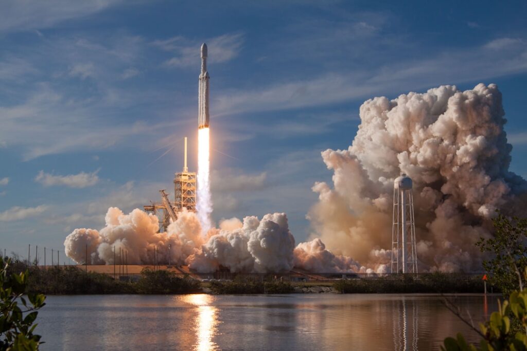 Starship Super Heavy booster fires methane-oxygen Raptors during vertical touchdown beside the launch tower.