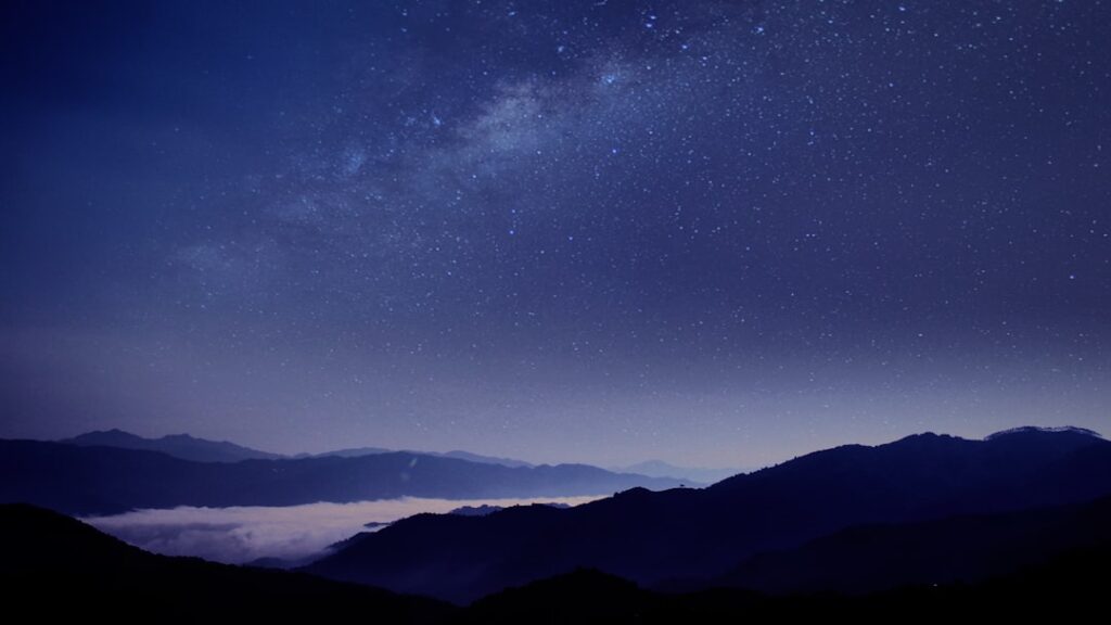 Night sky glows brilliant blue as a fast meteor streaks above Spanish rooftops, captured by security camera.