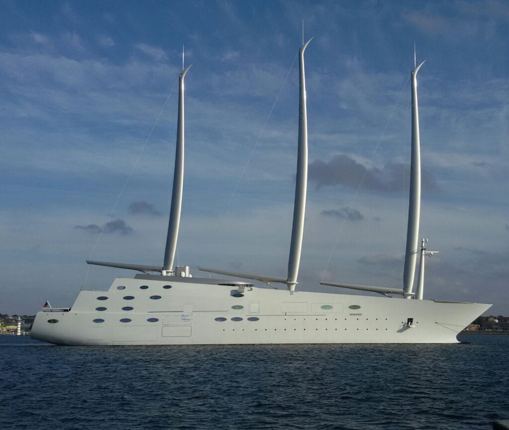 Rescue teams search near a partially submerged superyacht in open water, with recovery boats and divers visible.