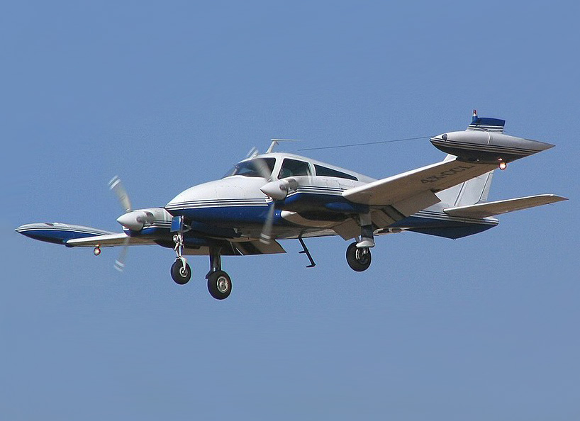 A Cessna 310 twin-engine plane wreckage on a highway near Boca Raton Airport, with emergency vehicles and responders at the scene.