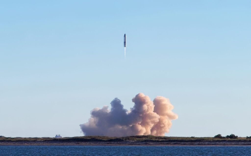 SpaceX Starship launches from Texas site at dusk with bright exhaust plume against sky